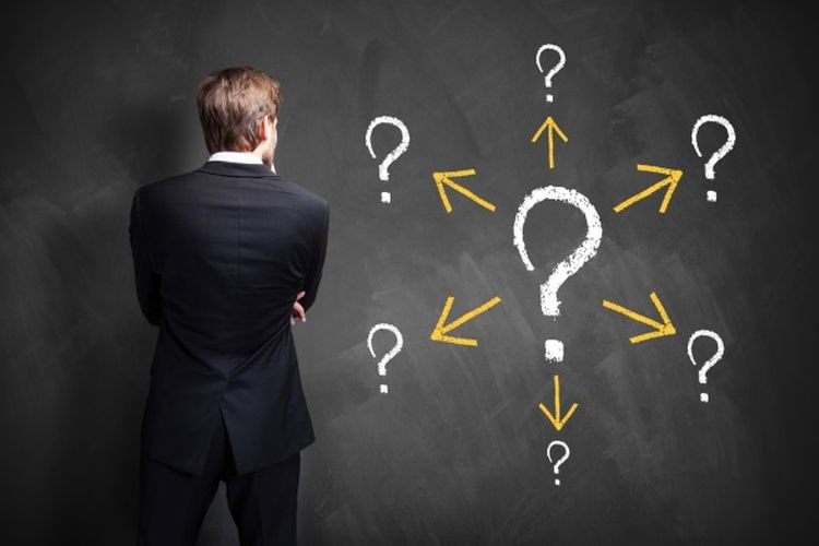 Person looking at chalkboard with many question marks