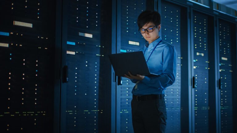 In Dark Data Center Male IT Specialist