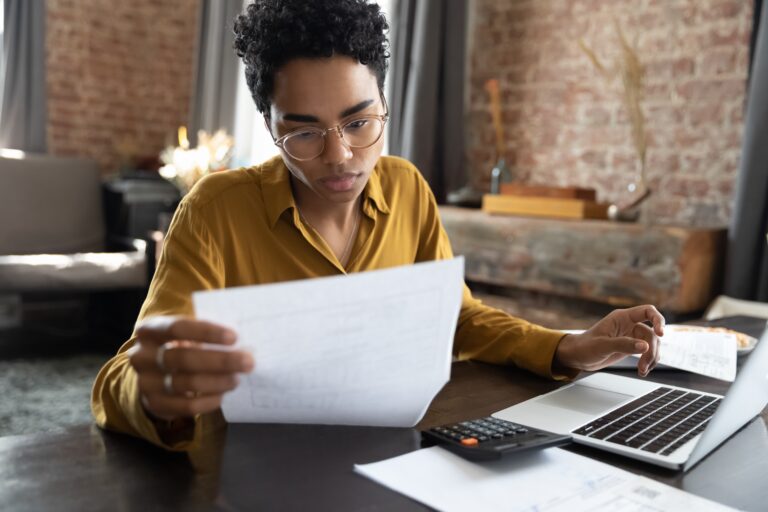 Focused Young African American Woman In Eyeglasses Looking Through Paper