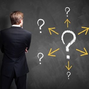 Person looking at chalkboard with many question marks