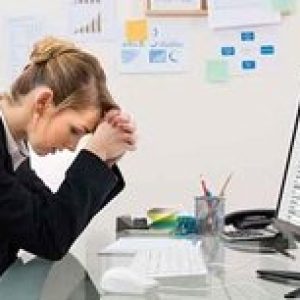Woman at desk looking concerned in front of a computer screen with a spreadsheet